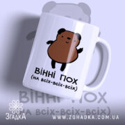 Чашка ведмідь пофігіст, біла з малюнком ведмедя, ракурс з правого боку, фон світло-синій, принт з ведмедем коричневого кольору, ручка стандартна, край рівний, матова поверхня.