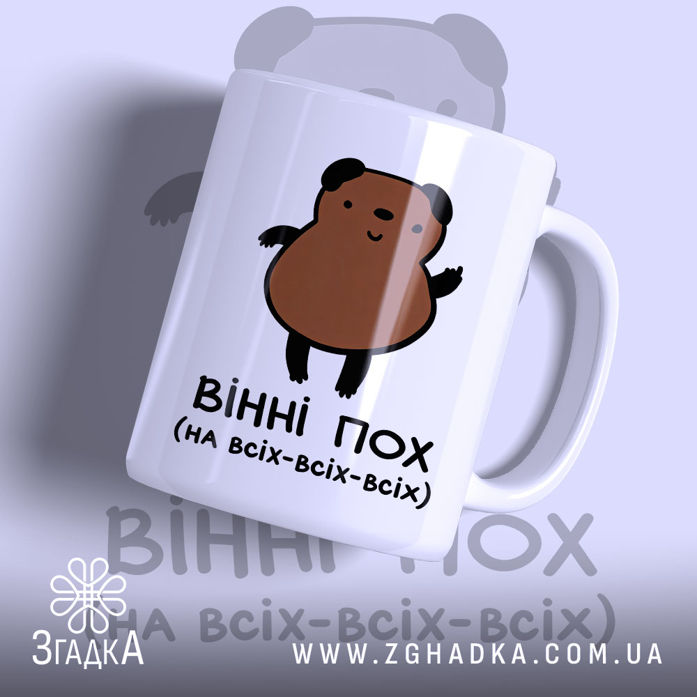 Чашка ведмідь пофігіст, біла з малюнком ведмедя, ракурс з правого боку, фон світло-синій, принт з ведмедем коричневого кольору, ручка стандартна, край рівний, матова поверхня.