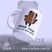 Чашка ведмідь пофігіст, біла з малюнком ведмедя, ракурс з правого боку, фон світло-синій, принт з ведмедем коричневого кольору, ручка стандартна, край рівний, матова поверхня.