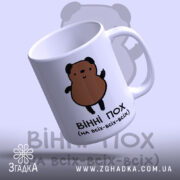 Чашка ведмідь пофігіст, біла з малюнком ведмедя, ракурс з правого боку, фон світло-синій, принт з ведмедем коричневого кольору, ручка стандартна, край рівний, матова поверхня.