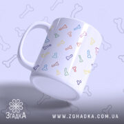 Чашка з кольоровими піструнами, біла з малюнками кісточок різних кольорів, зображена під кутом, фон світло-фіолетовий, ручка стандартна, край рівний, глянцева поверхня.