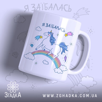 Чашка з втомленим єдинорогом, білого кольору, з ракурсом спереду, на фоні світло-фіолетового кольору, з принтом єдинорога на веселці, написом 'я заїбалась' у верхній частині, ручка стандартної форми, край рівний, глянцевий.