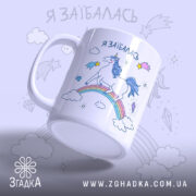 Чашка з втомленим єдинорогом, білого кольору, з ракурсом з боку, на фоні світло-фіолетового кольору, з принтом єдинорога на веселці, написом 'я заїбалась' у верхній частині, ручка стандартної форми, край рівний, глянцевий.