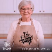 Фартух їж або готуй, бежевого кольору, зображений з ракурсу спереду на манекені, фон світлий, принт чорного кольору з написом 'Їж або готуй' та зображенням виделки і ножа.