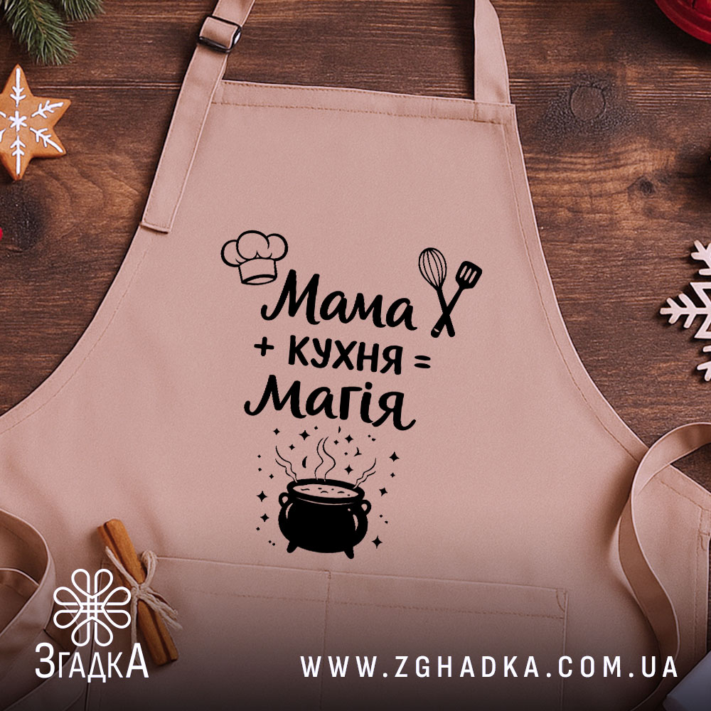 Фартух мама кухня магія, бежевий колір, зображений на дерев'яному фоні з декором, принт з текстом і малюнком казанка.