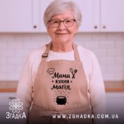 Фартух мама кухня магія, бежевий колір, зображений на манекені, фон світлий, принт з текстом і малюнком казанка.