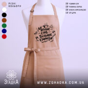 Фартух менше слів більше смаку. Бежевий фартух з чорним принтом, зображений на манекені, фон світлий, деталі принта включають кухонні атрибути, такі як каструля і спеції.