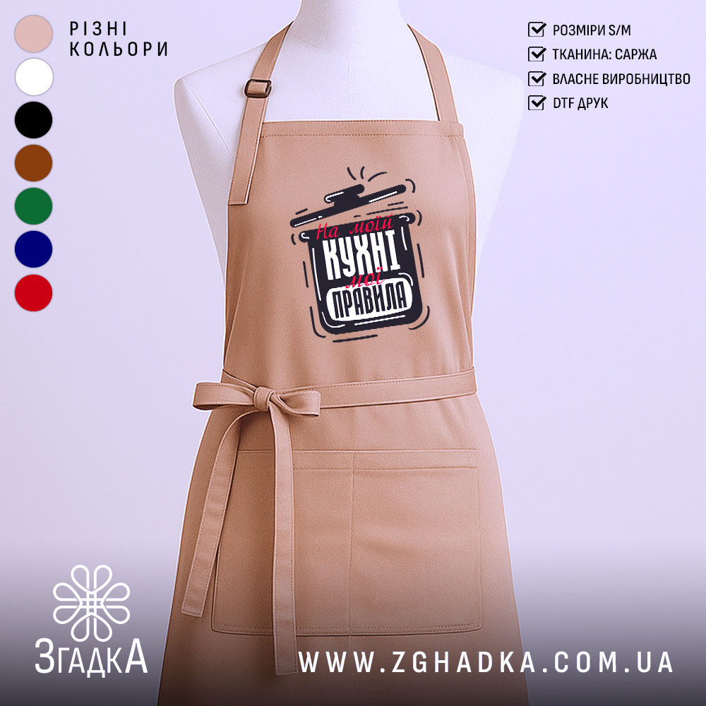 Фартух моя кухня правила. Фартух бежевого кольору, зображений з фронтального ракурсу, фон нейтральний, принт з написом "На моїй кухні мої правила" в чорному та червоному кольорах.