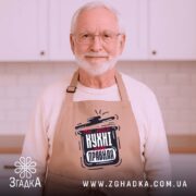 Фартух моя кухня правила. Фартух бежевого кольору, зображений з верхнього ракурсу, фон дерев'яний, принт з написом "На моїй кухні мої правила" в чорному та червоному кольорах, поруч декор у вигляді новорічних зірочок та печива.