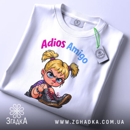 Футболка Adios Amigo білого кольору, зображена з верхнього ракурсу, на ній прикріплена етикетка, фон світлий, принт з малюнком дівчинки з пучками, яка показує середній палець, текст 'Adios Amigo' виконаний у кольорах рожевий та блакитний.