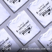 Футболка ангел на мітлі, біла, зображена на манекені, фон світло-сірий, принт чорного кольору з написом 'Я - ангел, чесне слово! Просто на мітлі ШВИДШЕ.' і малюнком мітли.