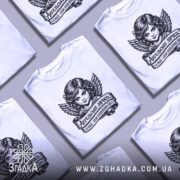 Футболка ангельське личко, біла, зображена на манекені, фон світло-сірий, принт з зображенням ангела з крилами та написом на стрічці.