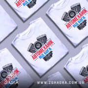 Футболка автомеханік від Бога — кілька складених футболок, композиція на столі.