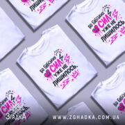 Футболка бабських сил. Біла футболка на манекені, з принтом у вигляді тексту чорного та рожевого кольорів, на фоні світло-сірого кольору. Принт містить елементи графіки, такі як блискавки та сердечка.