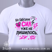 Футболка бабських сил. Біла футболка, складена на столі, з принтом у чорному та рожевому кольорах. На фоні світло-сірого кольору видно етикетку з зеленим шнурком.