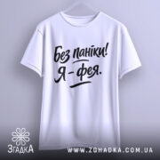 Футболка без паніки я фея, білого кольору, підвішена на вішалці, фон світло-сірий, принт чорного кольору з написом 'Без паніки! Я - фея.'