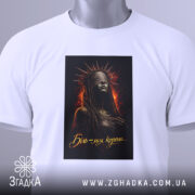 Футболка біль моя корона. Біла футболка, складена на поверхні, з принтом темної жінки в короні, фон з вогняними відтінками, на комірці видна етикетка.