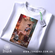 Футболка бунтарка стімпанк, біла, зображення моделі на футболці з етикеткою, ракурс зверху, фон з червоними і зеленими елементами, деталі принта включають шолом і годинник на підлозі.