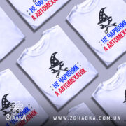 Футболка чарівник автомеханік, біла, зображена на манекені, фон нейтральний, принт містить чорний магічний капелюх з зірками та інструменти, текст червоний і синій.