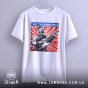 Футболка час прокинутись. Біла футболка, підвішена на вішалці, з принтом чоловіка, що грає на гітарі. Принт яскравий, з червоними променями, текст "ЧАС ПРОКИНУТИСЬ" розташований у верхній частині.