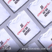 Футболка де справедливість, біла, зображена з правого ракурсу на манекені, фон світло-сірий, принт чорного та червоного кольорів з текстом 'ДЕ СПРАВЕДЛИВІСТЬ - НАС ТАМ НЕМЕЄ!'