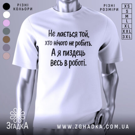 Футболка для тих хто працює. Біла футболка з чорним принтом, зображена з правого ракурсу на манекені. Фон світло-сірий, текст на футболці говорить: 'Не лається той, хто нічого не робить. А я піздець весь в роботі.'