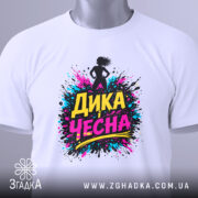 Футболка дика чесна, біла, складена на плоскій поверхні, фон світлий, принт з написом 'ДИКА ЧЕСНА' в яскравих кольорах, прикріплена етикетка з зеленим шнурком.