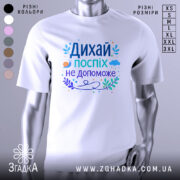 Футболка дихай спокійно, біла, зображена з фронтального ракурсу на манекені, фон нейтральний, принт містить текст "Дихай, поспіх не допоможе" в різних кольорах, з елементами рослинності та малюнком равлика.