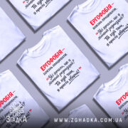 Футболка ергофобія гумор. Біла футболка на манекені, з принтом червоного та чорного кольору, на світлому фоні. Принт містить текст з жартом про ергофобію.