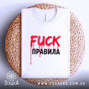 Футболка fuck правила, біла, складена на плетеній кошику, фон світло-сірий, принт червоний з краплями фарби та чорний текст.
