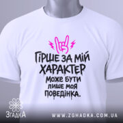 Футболка гірше ніж характер. Біла футболка, складена на столі, з принтом чорного кольору та рожевими елементами. На фоні світло-сірого кольору, видно етикетку з зеленим шнурком.