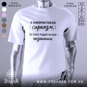 Футболка гострий сарказм, біла, зображена на манекені, фон світло-сірий, принт чорного кольору з текстом про сарказм.