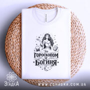 Футболка я богиня, біла, складена на плетеній основі, фон білий, принт чорного кольору з зображенням жінки та астрологічними елементами.