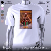 Футболка я маю подарунок, біла, з ракурсу спереду, на фоні розмитого інтер'єру з новорічними прикрасами, принт з зображенням чоловіка в червоній шапці Санти, який сидить на снігу з подарунком.