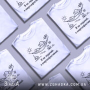 Футболка я не ледачий, біла, зображена на манекені, фон світло-сірий, принт з малюнком людини, що лежить у гамаку під сонцем, текст чорного кольору.