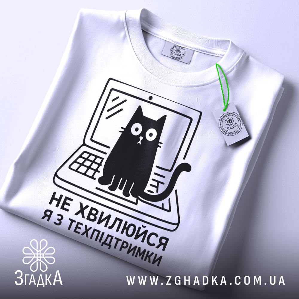 Футболка я з техпідтримки, білого кольору, зображена з верхнього ракурсу, на фоні світло-сірого кольору, принт чорного кольору з котом на ноутбуці та текстом 'НЕ ХВИЛЮЙСЯ Я З ТЕХПІДТРИМКИ', з етикеткою зеленого кольору.
