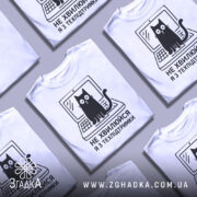 Футболка я з техпідтримки, білого кольору, зображена з фронтального ракурсу на манекені, фон світло-сірий, принт чорного кольору з котом на ноутбуці та текстом 'НЕ ХВИЛЮЙСЯ Я З ТЕХПІДТРИМКИ'.