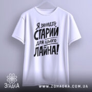 Футболка я занадто старий. Біла футболка, підвішена на вішалці, з легким боковим ракурсом. Фон світлий, з легким градієнтом. Принт чорного кольору, розташований по центру, з великими літерами.