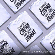 Футболка я занадто старий. Біла футболка з чорним принтом, зображена з близького ракурсу на манекені. Фон світлий, з легким градієнтом. Принт містить текст з великими літерами, що говорить про вік і ставлення до певних ситуацій.