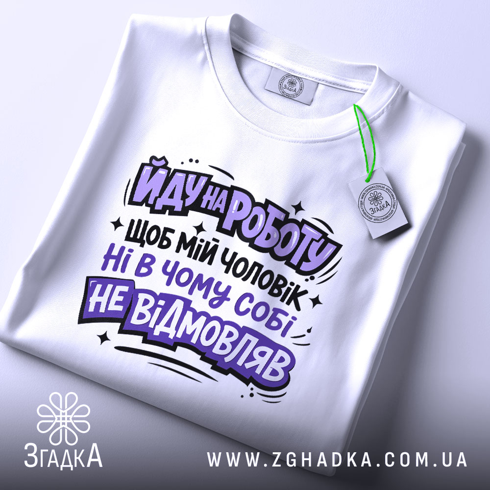 Футболка йду на роботу, біла, зображена зверху, на столі, фон світлий, принт чорного та фіолетового кольорів з текстом на українській мові, з етикеткою.