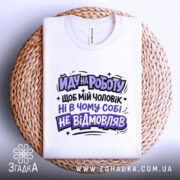 Футболка йду на роботу, біла, зображена зверху на плетеному кошику, фон світлий, принт чорного та фіолетового кольорів з текстом на українській мові.
