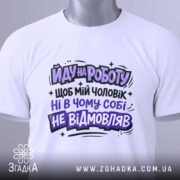 Футболка йду на роботу, біла, зображена зверху, на столі, фон світлий, принт чорного та фіолетового кольорів з текстом на українській мові, з етикеткою.