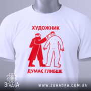 Футболка художник думає глибше, біла, зображена зверху, на столі, фон світло-сірий, принт червоного кольору з малюнком художника, що малює людину, з етикеткою на зеленому шнурку.