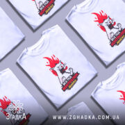 Футболка контроль без паніки. Біла футболка з коротким рукавом, зображена на манекені з металевим покриттям. Принт зображує кота з червоним полум'ям на фоні, текст на футболці чорного та червоного кольору.