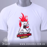 Футболка контроль без паніки. Біла футболка, складена на столі, з видимим принтом кота з червоним полум'ям. На футболці є етикетка з зеленим шнурком.