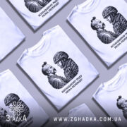 Футболка козацькому роду нема переводу. Біла футболка з коротким рукавом, зображення на грудях у вигляді двох чоловіків, один у козацькому одязі, інший у військовій формі, принт чорного кольору, фон світлий, футболка представлена на манекені.