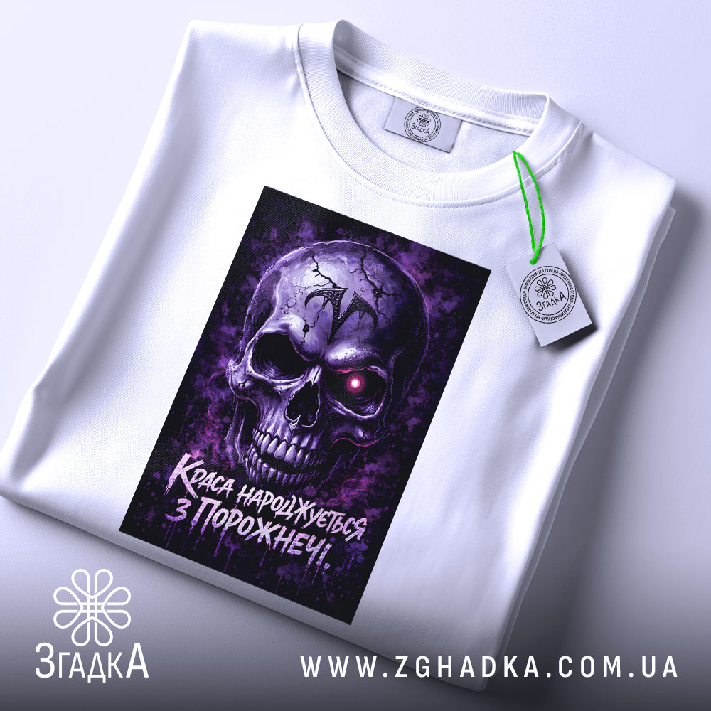 Футболка краса з порожнечі, біла, зображена в горизонтальному положенні, фон світлий, принт з черепом у фіолетових тонах, на футболці є етикетка з зеленим шнурком.