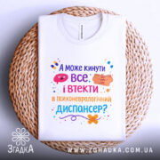 Футболка кинути все і втекти. Біла футболка, складена на плетеній кошику. Фон світло-сірий. Принт яскравий, з текстом і графічними елементами, що запитують про можливість відвідати психоневрологічний диспансер.