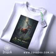 Футболка ліс знає ким я є, біла, зображена з верхнього ракурсу, на фоні світлого кольору, принт з оленями в лісі, з етикеткою на зеленому шнурку.