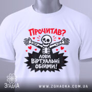 Футболка лови віртуальні обійми, біла, зображена зверху, складена на плоскій поверхні, фон світло-сірий, принт з черепом, що розпростерті руки, червоні сердечка та текст "Прочитав? Лови віртуальні обійми!", на етикетці зелена стрічка.